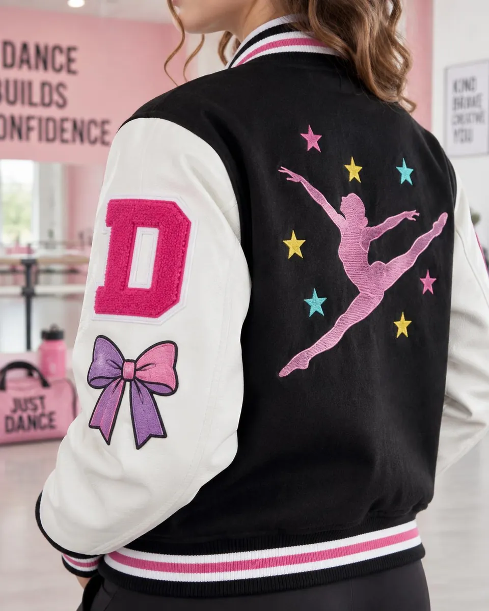 Close-up of a varsity jacket sleeve and back with a pink chenille letter, embroidered dancer silhouette, stars and bow patches