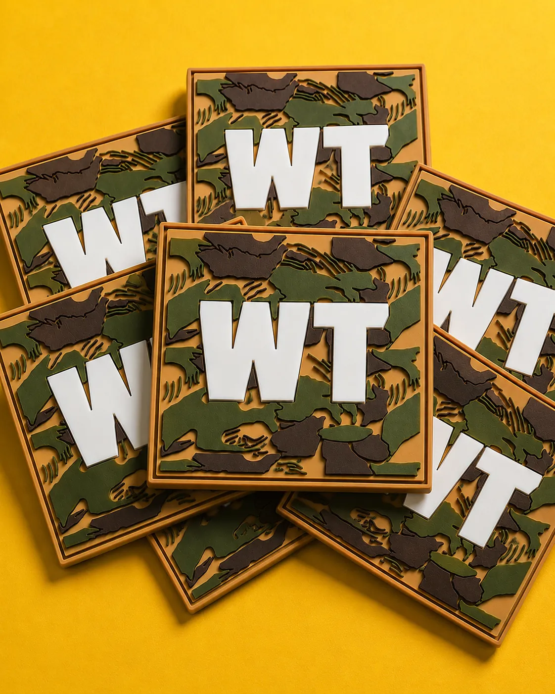 Stacked WT camo PVC patches on yellow background